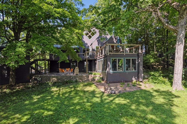 rear view of house with a wooden deck, a patio area, and a yard