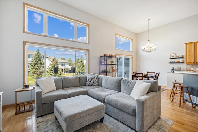 living room featuring a towering ceiling, an inviting chandelier, and light hardwood / wood-style floors