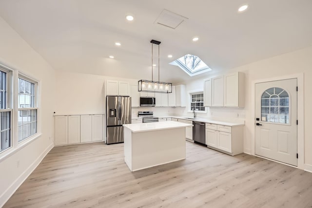 kitchen with stainless steel appliances, sink, decorative light fixtures, light hardwood / wood-style flooring, and a kitchen island