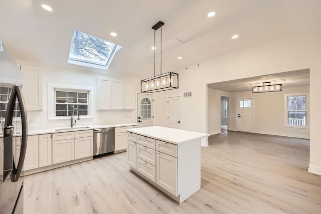 kitchen with appliances with stainless steel finishes, light wood-type flooring, sink, pendant lighting, and white cabinets