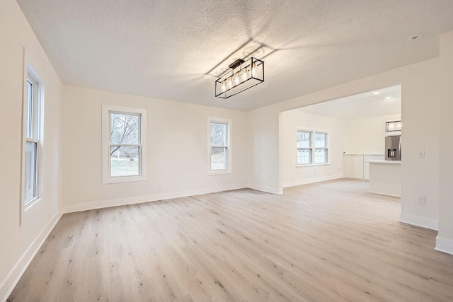 unfurnished living room featuring a textured ceiling and light hardwood / wood-style flooring