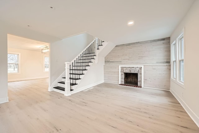 unfurnished living room with light hardwood / wood-style floors and wood walls