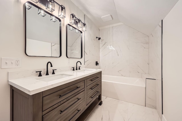 bathroom with vanity, tiled shower / bath, and vaulted ceiling