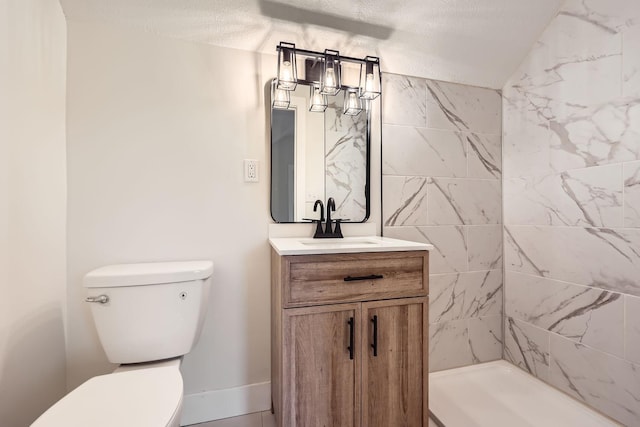 bathroom with tiled shower, vanity, a textured ceiling, and toilet