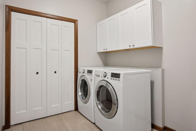 washroom featuring cabinets, washer and dryer, and light hardwood / wood-style flooring