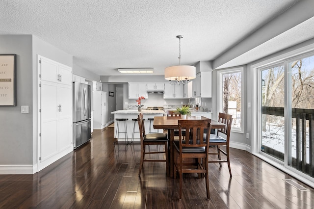 dining area featuring a textured ceiling, dark hardwood / wood-style flooring, and a notable chandelier