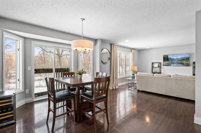 dining area featuring dark wood-type flooring, a wealth of natural light, and a notable chandelier