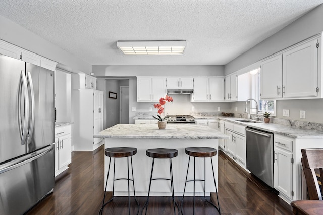 kitchen with a center island, sink, white cabinetry, stainless steel appliances, and dark hardwood / wood-style flooring