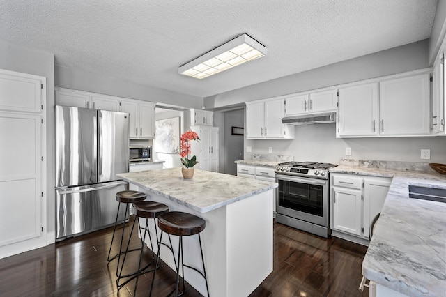 kitchen with white cabinets, appliances with stainless steel finishes, a textured ceiling, and a kitchen island