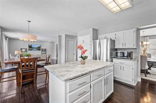 kitchen featuring white cabinetry, hanging light fixtures, appliances with stainless steel finishes, and a center island