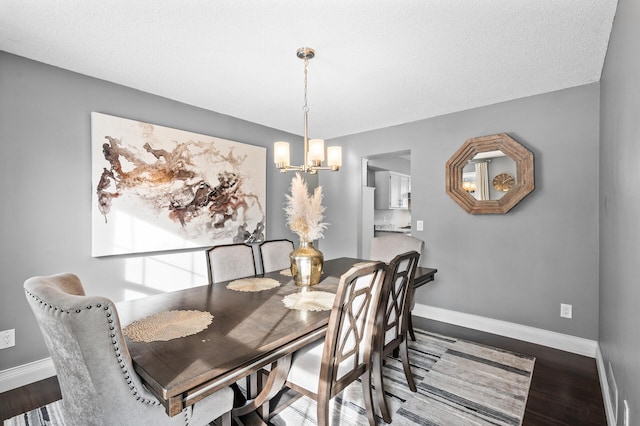 dining area featuring wood-type flooring, a notable chandelier, and a textured ceiling