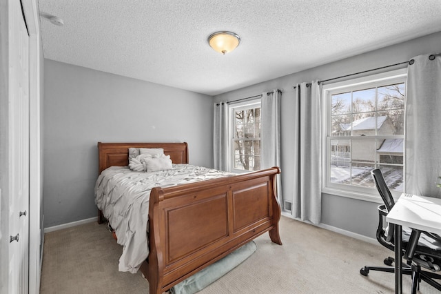 bedroom with a textured ceiling, light colored carpet, and multiple windows