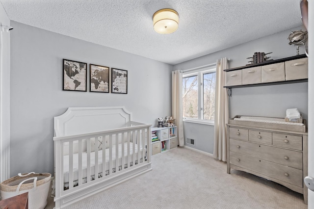 carpeted bedroom with a crib and a textured ceiling