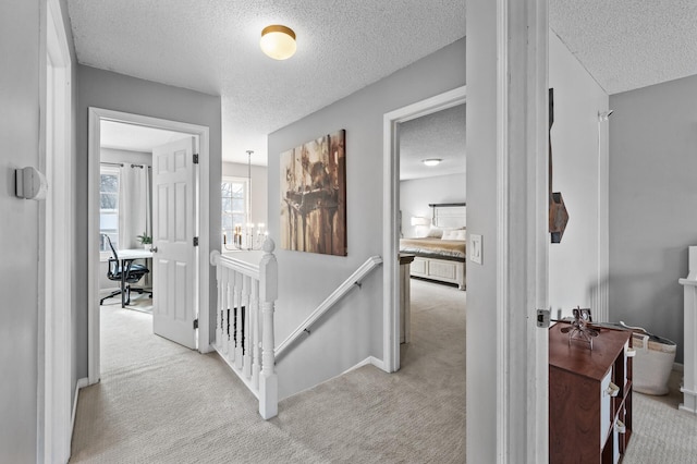 corridor featuring a textured ceiling and light carpet