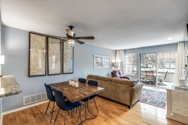 dining room with ceiling fan, light wood-type flooring, and a textured ceiling