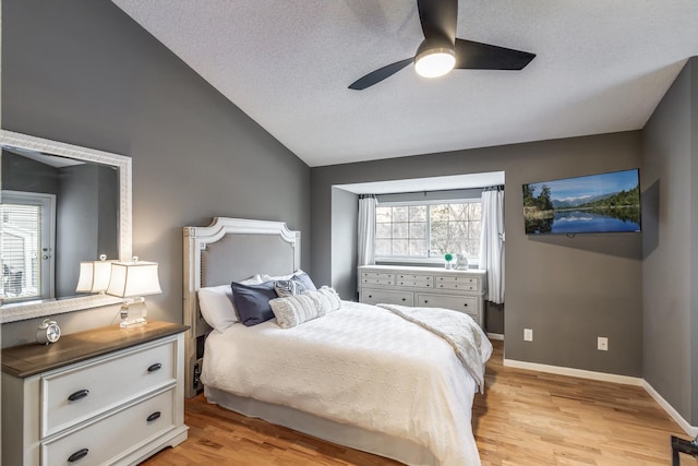 bedroom with ceiling fan, light hardwood / wood-style floors, a textured ceiling, and vaulted ceiling