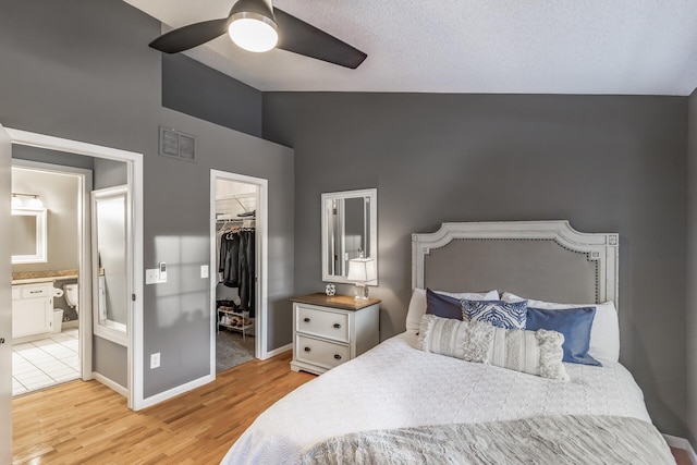 bedroom featuring a walk in closet, ensuite bath, ceiling fan, light hardwood / wood-style floors, and a closet