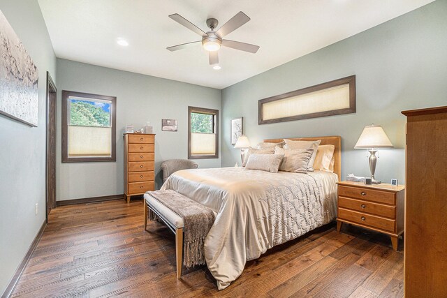 bedroom with ceiling fan, dark wood-type flooring, and multiple windows