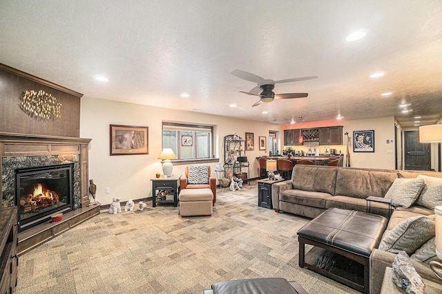 living room featuring light carpet, a textured ceiling, ceiling fan, indoor bar, and a fireplace