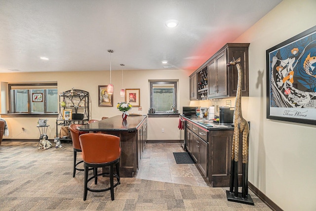 kitchen featuring a kitchen breakfast bar, a center island, dark brown cabinets, and hanging light fixtures