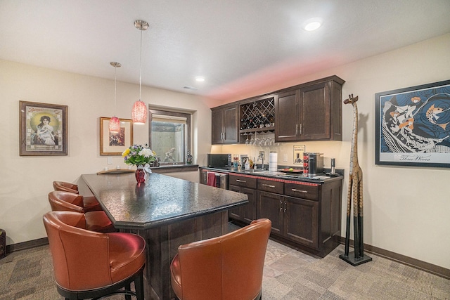 kitchen featuring pendant lighting, a kitchen breakfast bar, dark brown cabinetry, and sink