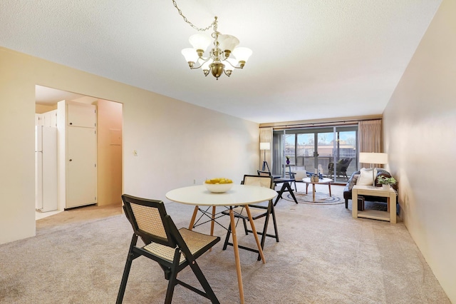 dining room featuring light colored carpet, a textured ceiling, and a chandelier