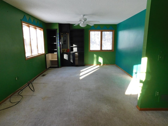 carpeted empty room featuring ceiling fan and a textured ceiling