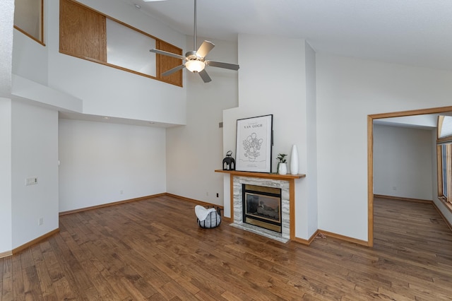 unfurnished living room featuring ceiling fan, high vaulted ceiling, dark hardwood / wood-style floors, and a fireplace