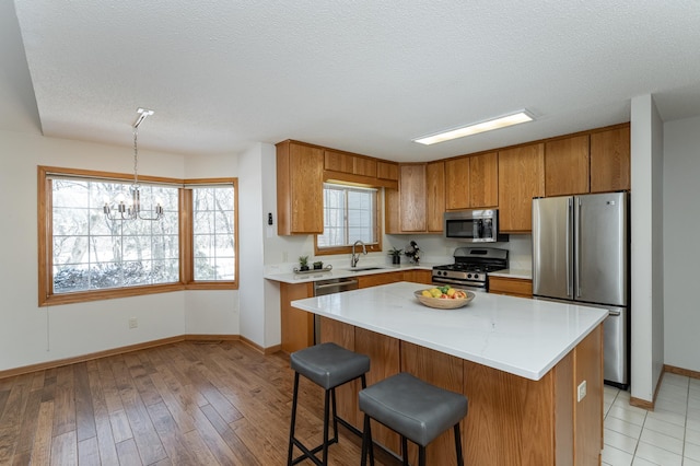 kitchen featuring a kitchen island, appliances with stainless steel finishes, sink, and a textured ceiling