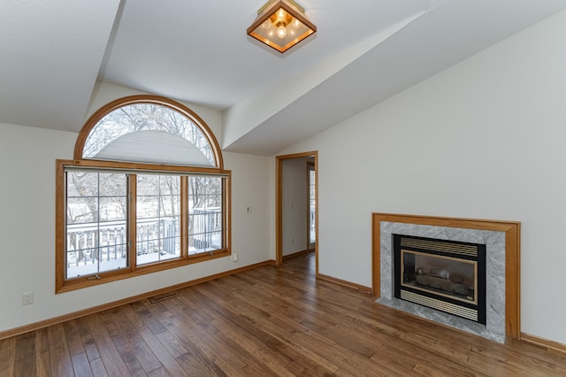 unfurnished living room with dark wood-type flooring, lofted ceiling, and a premium fireplace