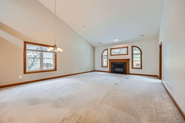 unfurnished living room with a notable chandelier, light carpet, high vaulted ceiling, and a tiled fireplace