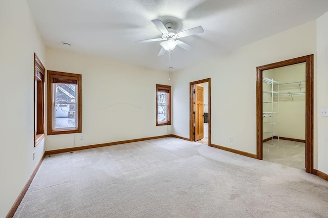 unfurnished bedroom featuring connected bathroom, multiple windows, ceiling fan, and light colored carpet