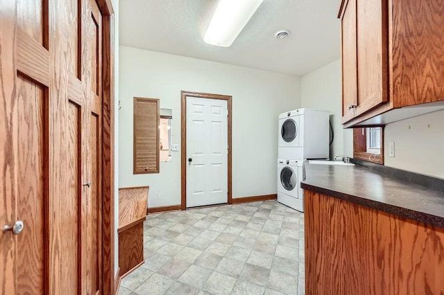 laundry area with stacked washer / dryer, sink, and cabinets