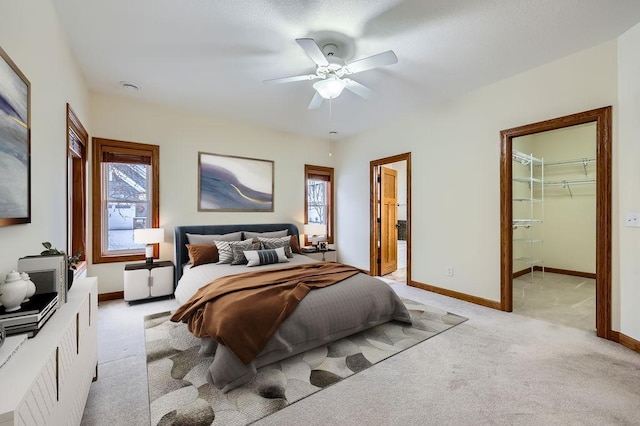 bedroom with ensuite bath, a spacious closet, ceiling fan, and light carpet