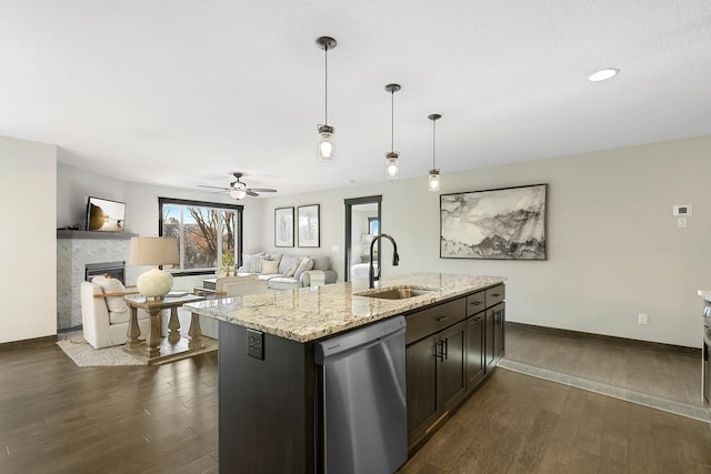 kitchen featuring dishwasher, a center island with sink, sink, ceiling fan, and light stone counters