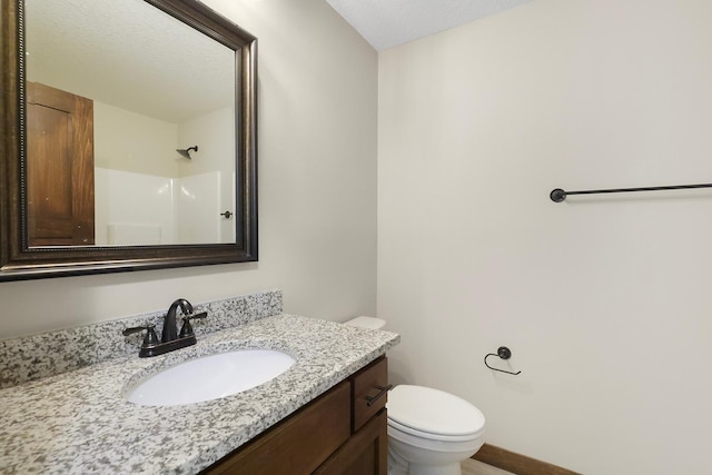 bathroom featuring vanity, toilet, a textured ceiling, and walk in shower