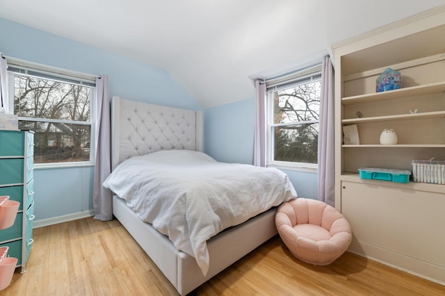 bedroom with light hardwood / wood-style floors, multiple windows, and lofted ceiling