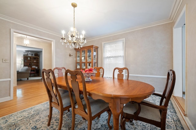 dining area with a chandelier, light hardwood / wood-style flooring, and crown molding