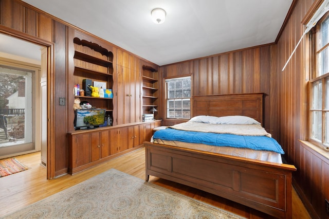 bedroom with wood walls and light hardwood / wood-style floors