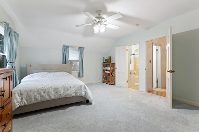 bedroom with connected bathroom, light colored carpet, vaulted ceiling, and ceiling fan