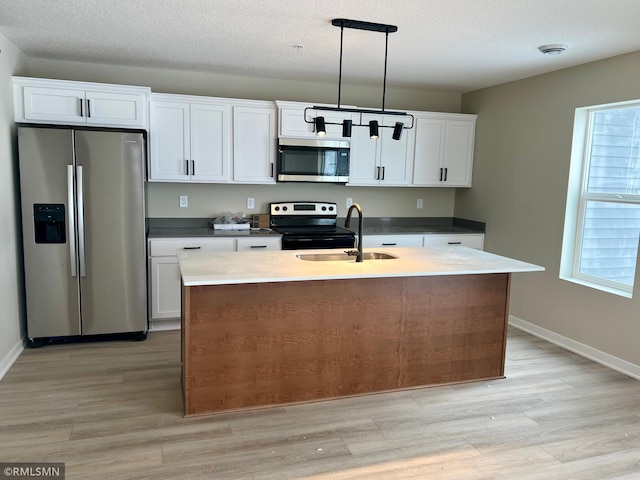 kitchen with appliances with stainless steel finishes, sink, white cabinetry, and pendant lighting