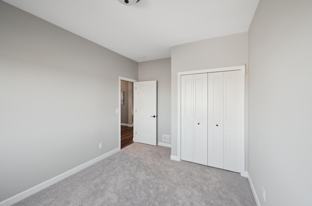 unfurnished bedroom with a closet and light colored carpet