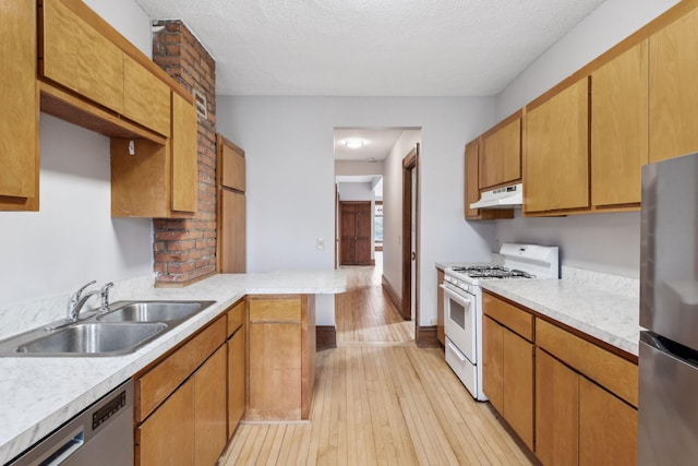 kitchen with sink, appliances with stainless steel finishes, a textured ceiling, and light hardwood / wood-style flooring