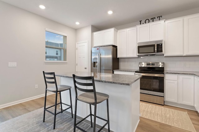 kitchen featuring dark stone counters, white cabinetry, a center island, and stainless steel appliances