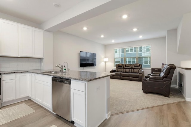 kitchen featuring stainless steel dishwasher, sink, dark stone countertops, white cabinets, and light hardwood / wood-style floors