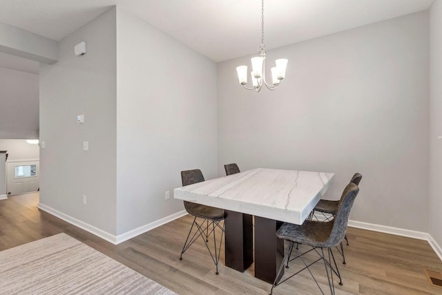 dining area with wood-type flooring and an inviting chandelier