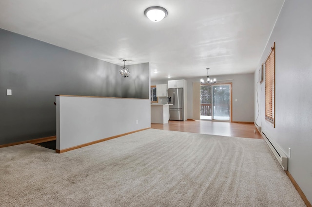 unfurnished living room featuring baseboard heating, light colored carpet, and an inviting chandelier