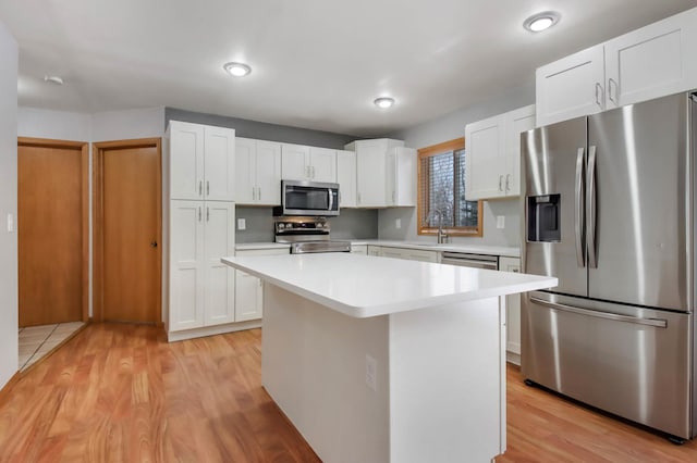 kitchen featuring sink, light hardwood / wood-style flooring, appliances with stainless steel finishes, white cabinetry, and a kitchen island