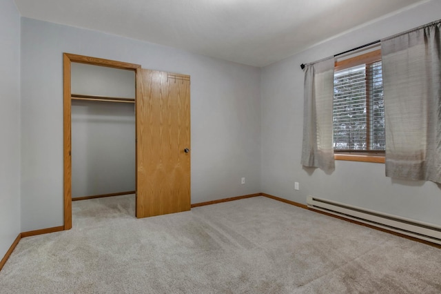 unfurnished bedroom with a baseboard radiator, a spacious closet, a closet, and light carpet