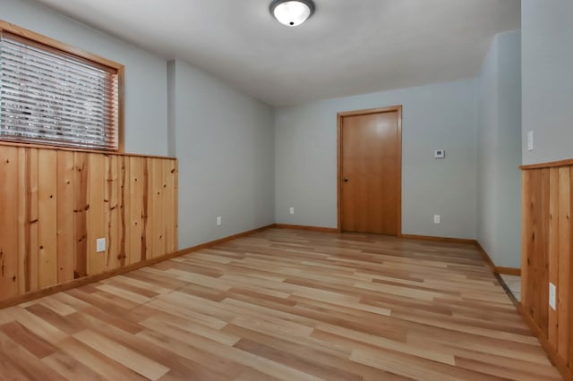 unfurnished room featuring wooden walls and light hardwood / wood-style floors